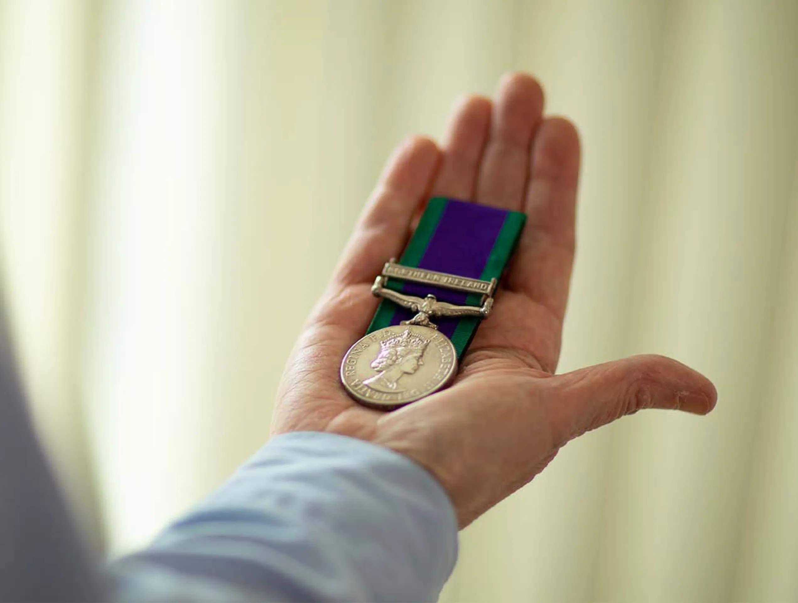 Photo of a UK Armed Forces veteran's hand holding a service medal.
