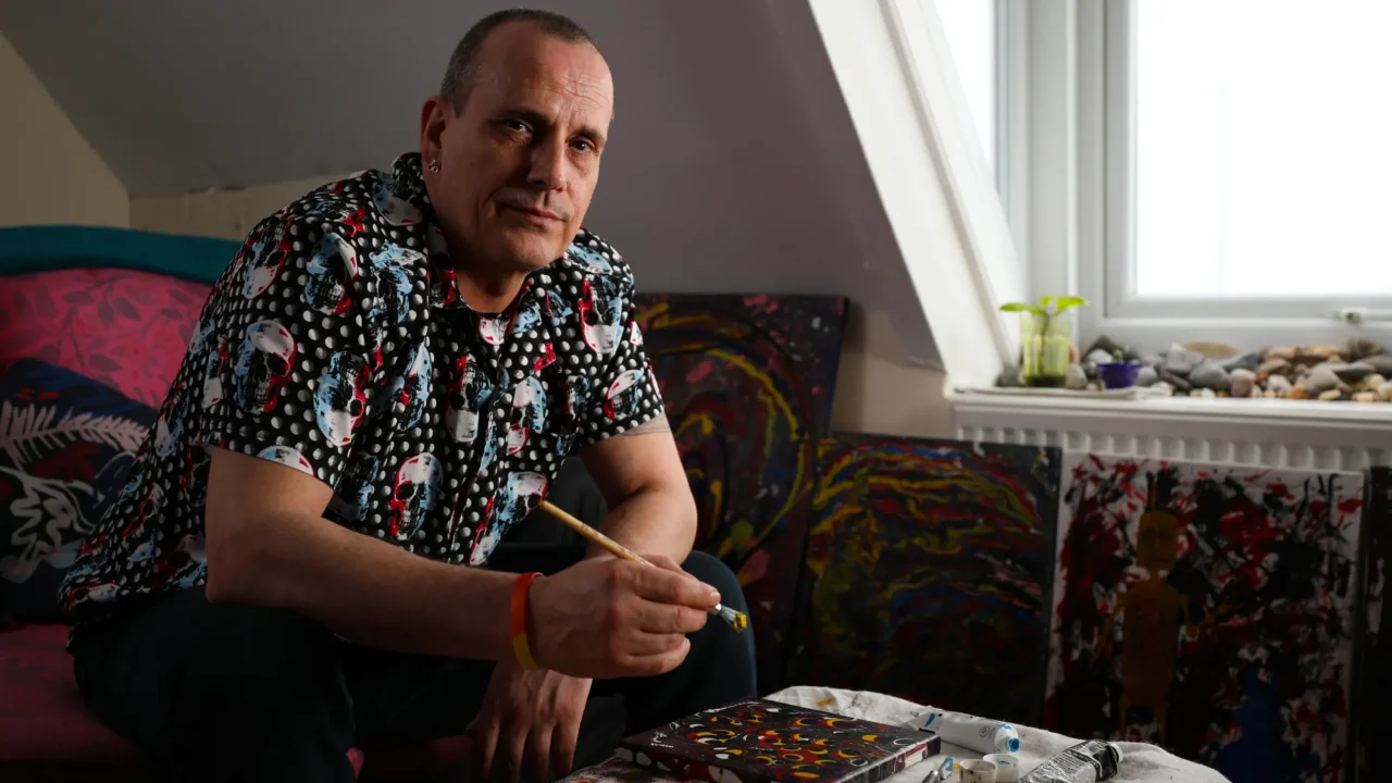 Portrait photo of a male UK Armed Forces veteran holding a paintbrush above a canvas.