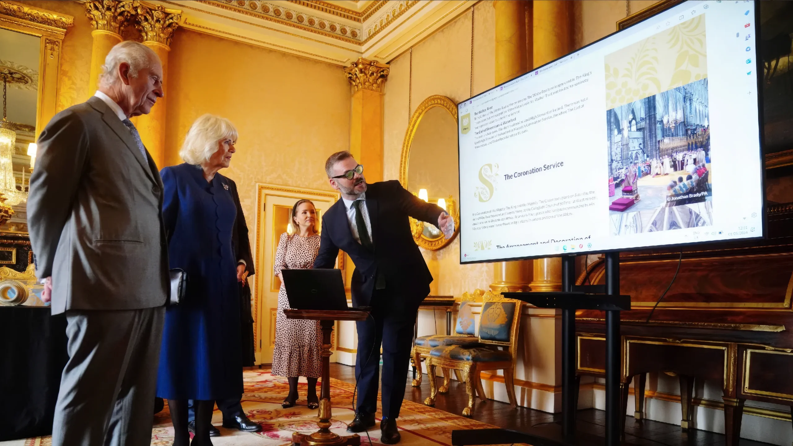 king charles and queen camilla looking at the Coronation Roll on a large screen
